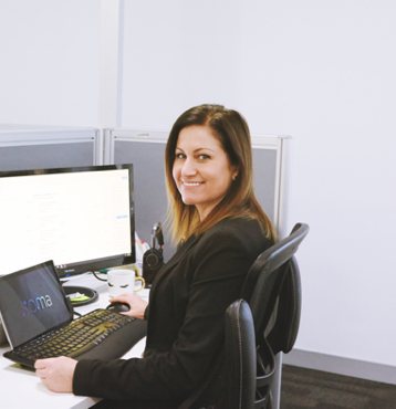 Woman smiling at camera and sitting at laptop