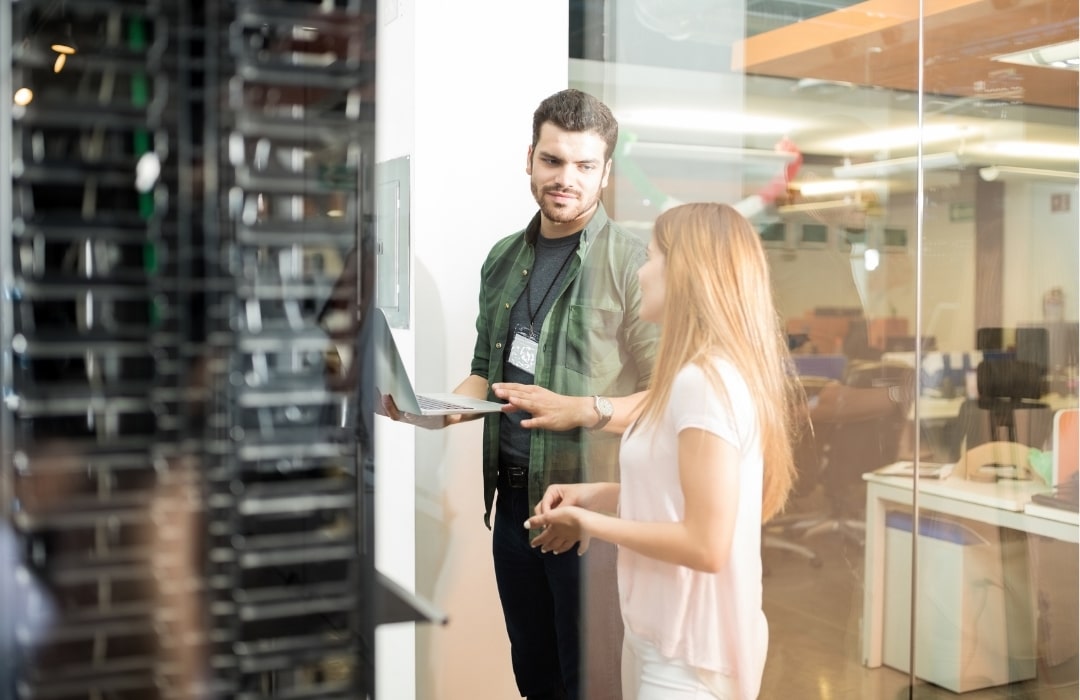 [IT Man and Office Woman Standing Next To Server Unit] | Onsite and Offsite Backup - Benefits of Offsite Backup | Blog Featured Image